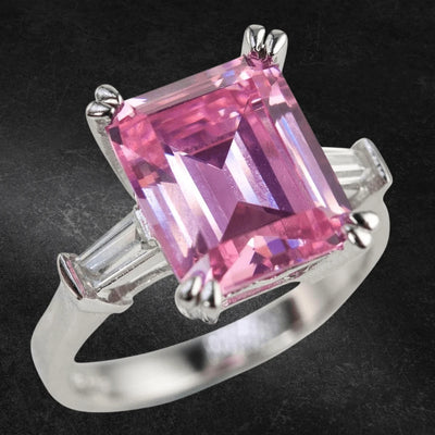 Pink Billionaire Ladies Ring featuring a large square-cut pink gemstone set in sterling silver with rhodium plating and tapered clear side stones, designed for women.