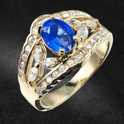 Regency Sapphire Ring featuring a sterling silver band with gold plating, showcasing a vibrant blue sapphire center stone surrounded by sparkling clear gemstones, designed for women.