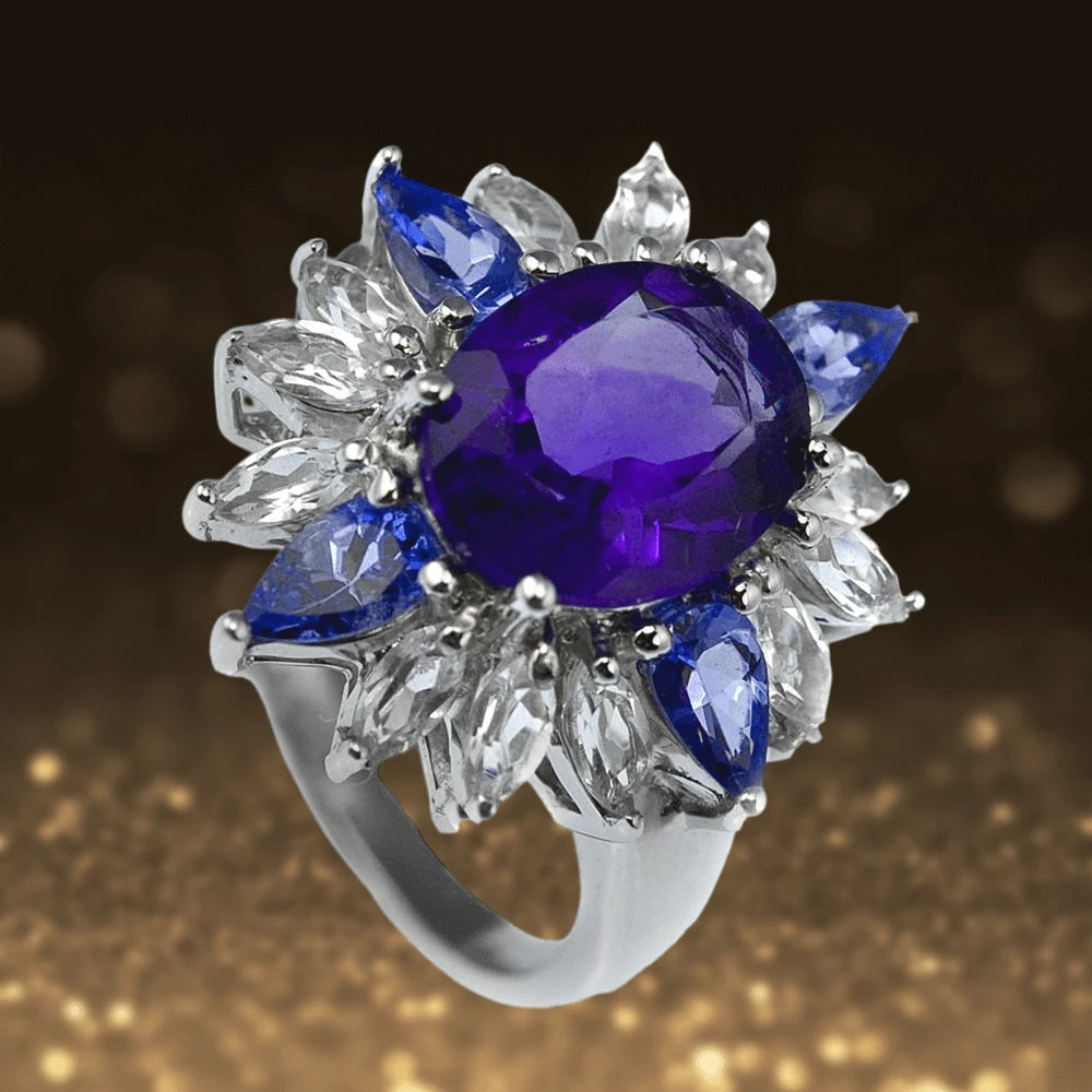 Super Nova Ring featuring a large oval purple gemstone surrounded by marquise-shaped blue and clear stones on a sterling silver band plated with rhodium, designed for women.
