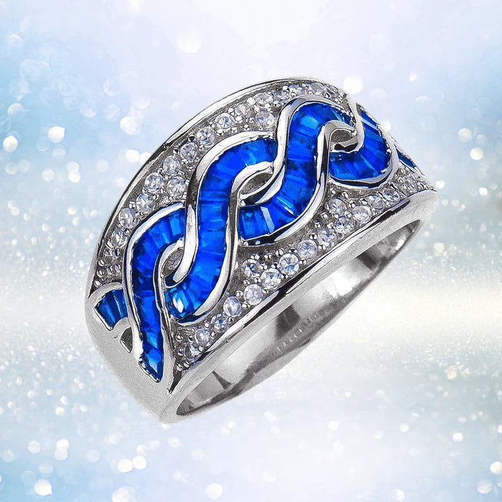 Charleston Ring featuring a sterling silver band with rhodium plating, adorned with a swirling pattern of deep blue stones and sparkling clear crystals, designed for women’s jewelry.