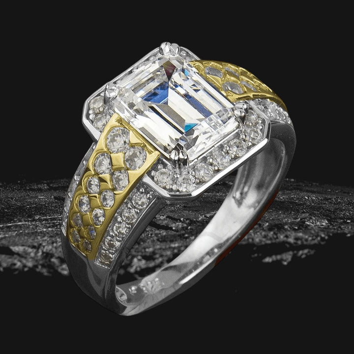 Fineza Ring featuring a two-tone sterling silver band with intricate gold plating and a large emerald-cut center stone, surrounded by smaller sparkling diamonds.