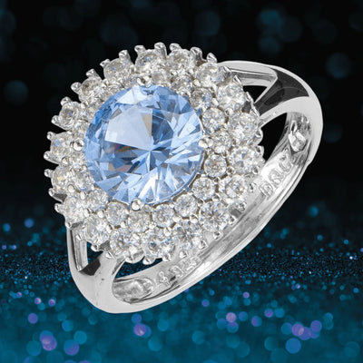 Idols Eye Ring featuring a large round blue gemstone surrounded by sparkling clear stones, set in sterling silver with rhodium plating for a luxurious female jewelry piece.