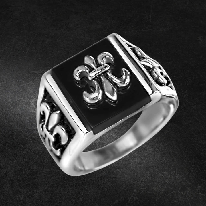 Grand Canyon Steel Ring featuring a bold stainless steel design with a black square face and intricate fleur-de-lis patterns, crafted for men’s jewelry collections.