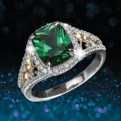 Aurora Ring featuring a two-tone sterling silver band with intricate gold details and a large radiant green gemstone centerpiece surrounded by small clear stones.