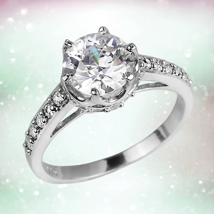 Crown Ring featuring a sterling silver band with rhodium plating, adorned with a large round clear gemstone centerpiece and smaller sparkling stones along the band, designed for females.