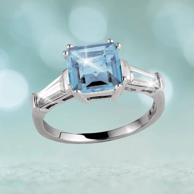Decadence Gem Ring Blue Topaz featuring a square blue topaz center stone set in sterling silver with rhodium plating, designed for a female jewelry collection.
