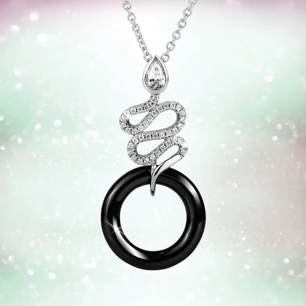 Ceramica Serpent Pendant featuring a sterling silver rhodium-plated snake design adorned with sparkling stones wrapping around a black circular ceramic ring on a delicate chain.