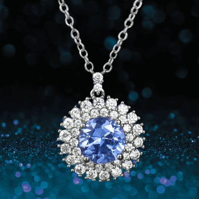 Idols Eye Pendant featuring a round blue gemstone surrounded by sparkling clear stones, set in sterling silver with rhodium plating, designed for women’s jewelry.