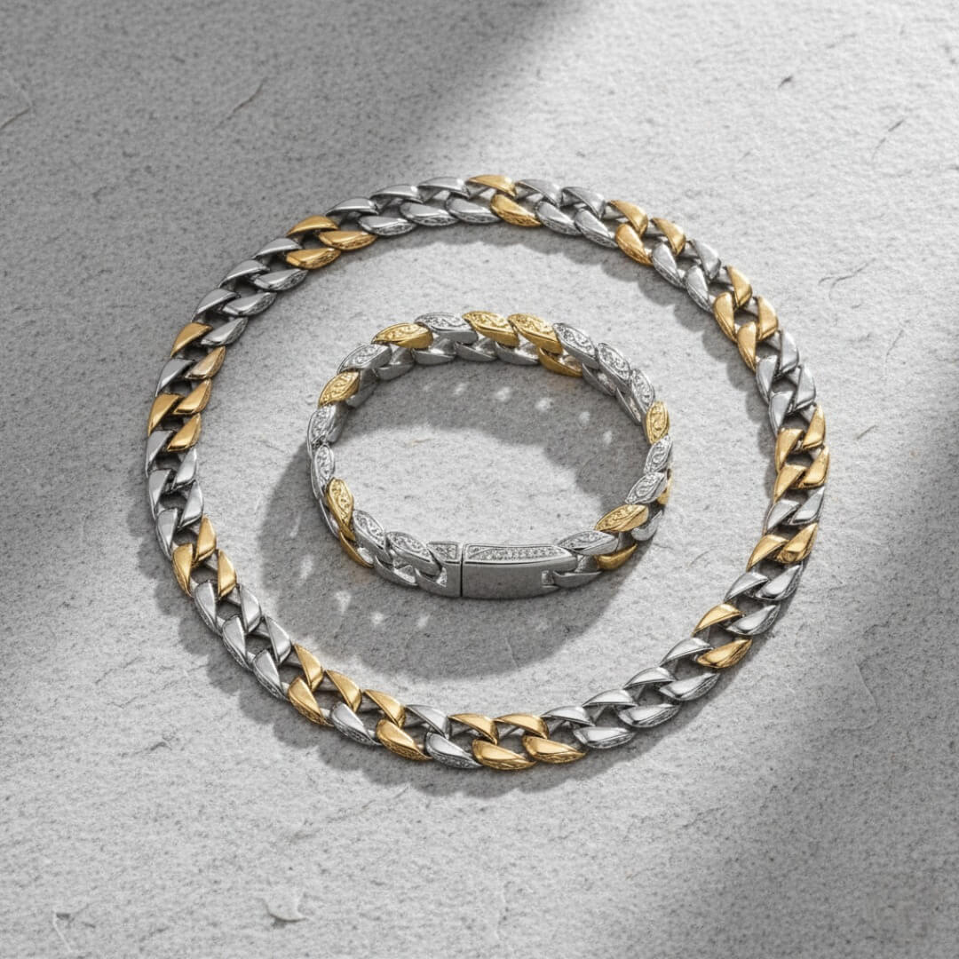 Two silver and gold chain necklaces on a textured gray surface.  Curb Vine Men's Set by Daniel Steiger