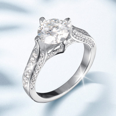 Novalyn Moissanite Ring featuring a large round center stone with a split shank band adorned with smaller sparkling accents in polished silver-tone metal.