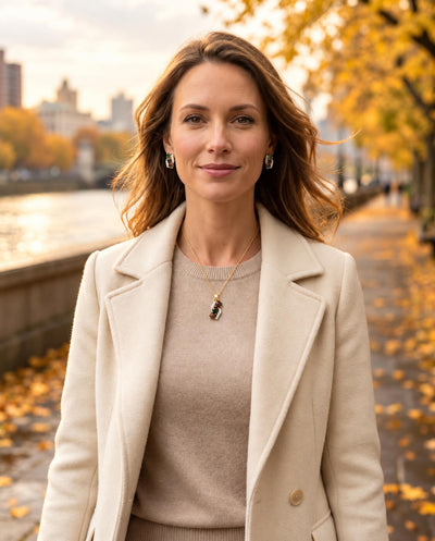 Ember & Eclipse Opal Earrings worn by a woman in a cream coat, featuring elegant opal drops against a warm autumn city backdrop