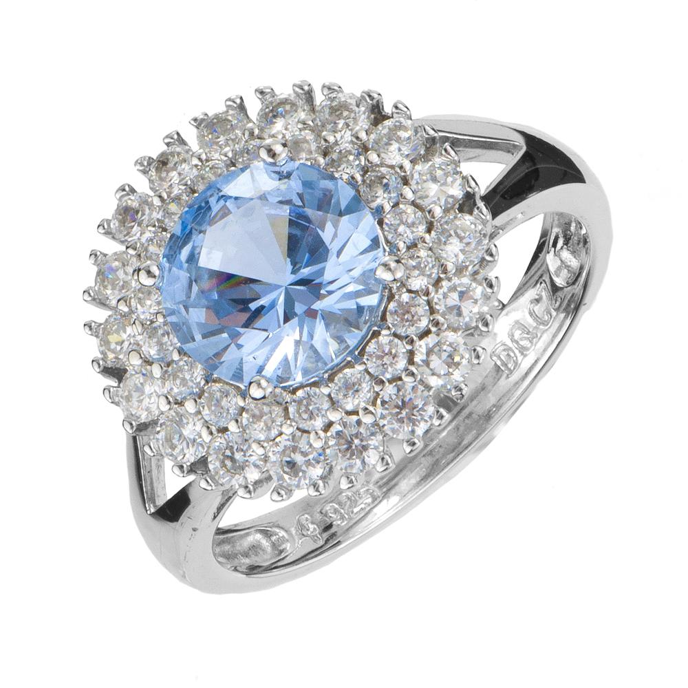 Idols Eye Ring featuring a sterling silver band with rhodium plating, adorned with a large blue gemstone center surrounded by sparkling clear stones, designed for women’s jewelry.