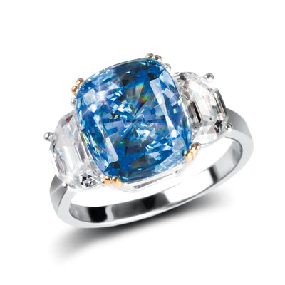 Sapphira Ring featuring a two-tone sterling silver band with a large vibrant blue center gemstone flanked by two clear emerald-cut stones, designed for women’s jewelry.
