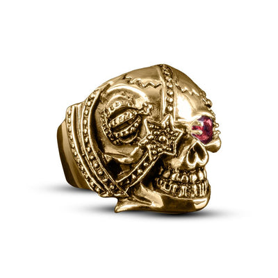 Riotous Skull Ring in gold-plated stainless steel featuring an ornate skull design with detailed embellishments and a red gemstone eye, crafted for men’s jewelry.