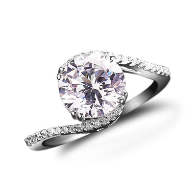 Embrace Solitaire Ring for female in sterling silver with rhodium plating, featuring a large round solitaire stone and a twisted band adorned with smaller stones.